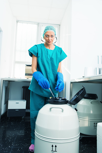 laboratory worker holding samples above a cryogenic tank